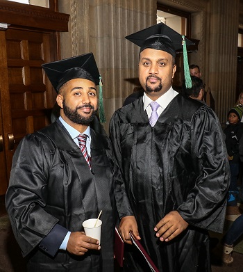 Two Students wearing Graduation cap and gown posing for a picture