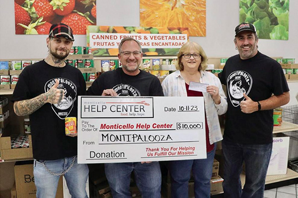 MontiPalooza founders Zach Barthel, left, Lloyd Hilgart, center, and Andy Duszynski, right, present a check for $10,000 to Monticello Help Center Executive Director Mary Gardner. The money was raised during an October 7 series of concerts at Nordic Brewpub