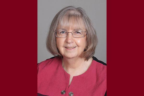 A woman wearing a red shirt and eyeglasses, posing for a photo