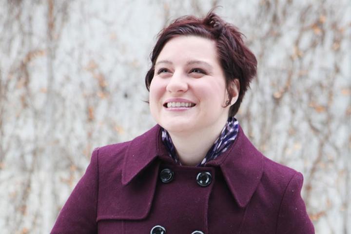 A woman wearing a purple winter coat, posing for a photo